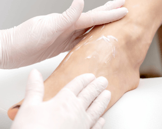 Voetverzorging met hydraterende crème aangebracht door een pedicure.