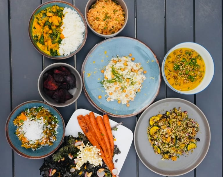 a table with bowls of vegetarian plant-based food and a bowl of vegetables carrots chickpeas
