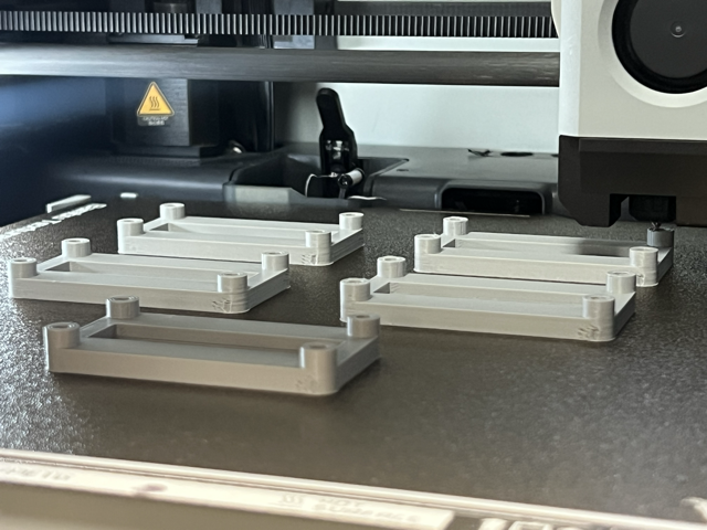 Batch production of custom 3D printed components and brackets on an industrial FDM 3D printer bed.