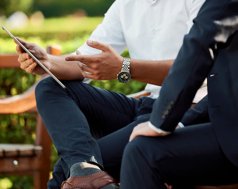 Executive is sitting and discussing a plan on the tablet with his assistant