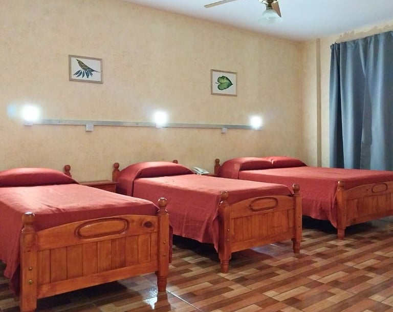 Una habitación con tres camas y un ventilador de techo.