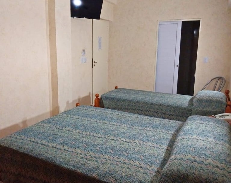 Una habitación con dos camas y un televisor de pantalla plana.