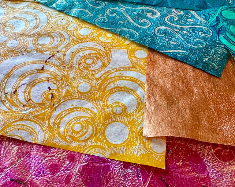 Stack of hand-painted collage papers with gold pattern and vibrant colors