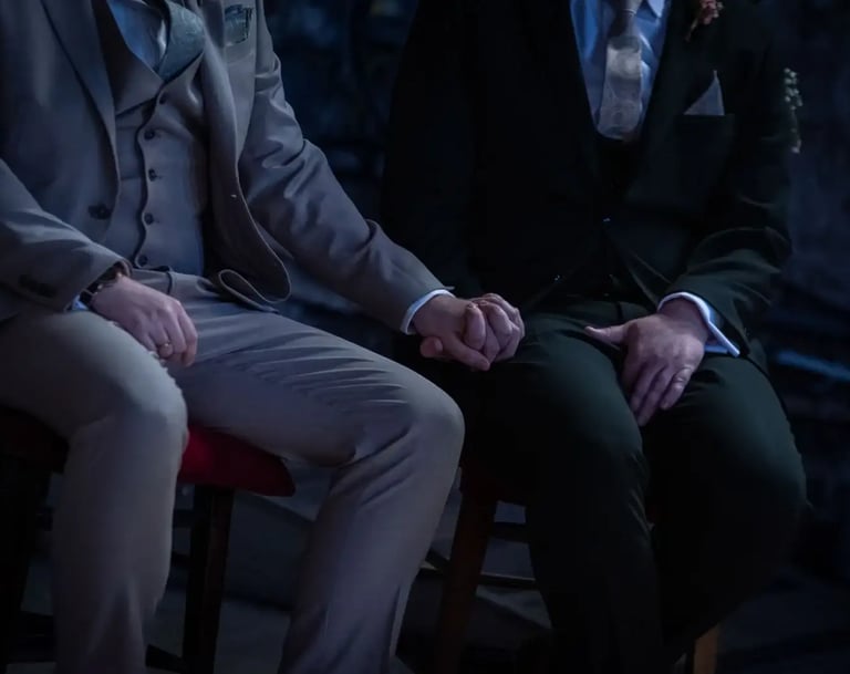 two grooms sitting holding hands
