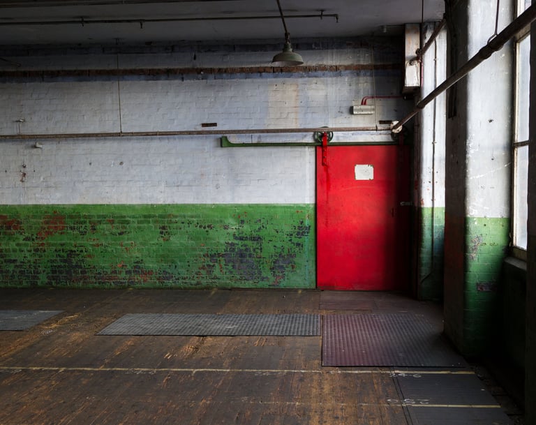 Peeling paint with an industrial original iron door with original wooden floors in the Main Room at Atlas Studios.