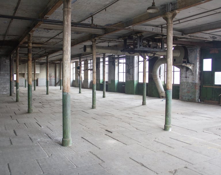 Image showing the industrial ironworks, peeling paint, stone floor and metal columns in the Stone room at Atlas Studios