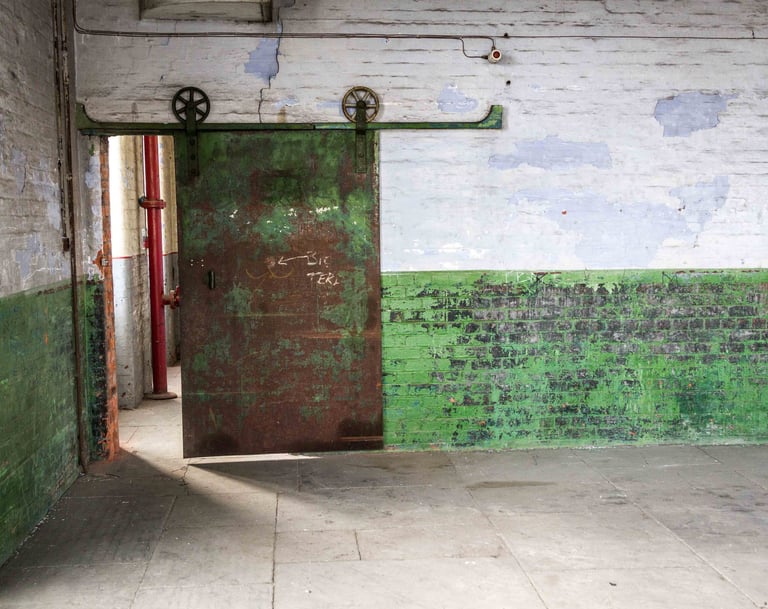 Original iron sliding door, peeling paint of the textured walls and stone floor in the Stone Room at Atlas Studios