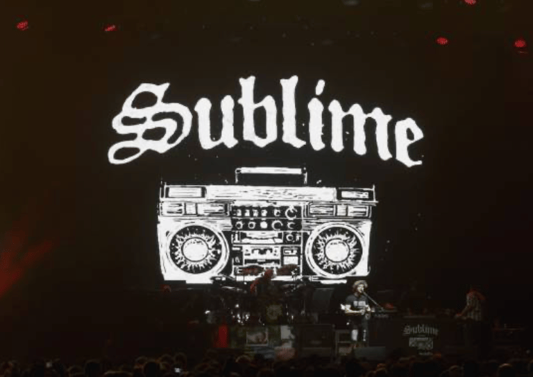 The band Sublime performing on stage with a large boombox graphic and logo backdrop.