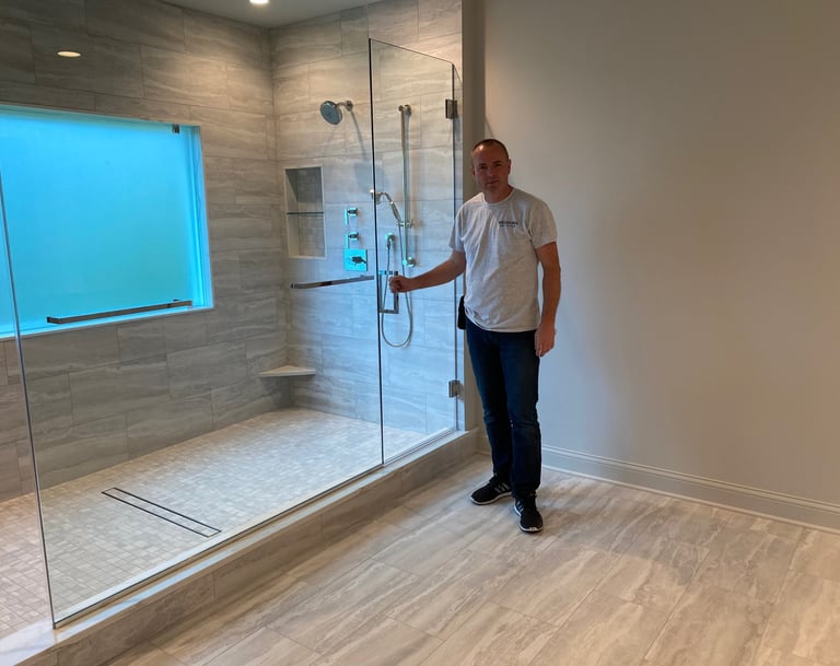 Wes contractor showing a newly installed frameless glass walk-in shower with gray tiles.