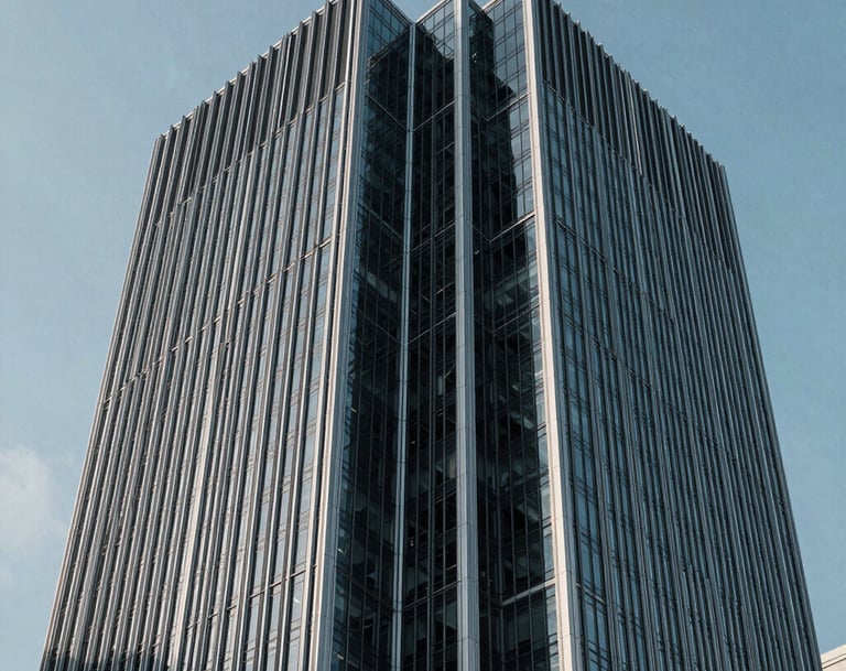 Architectural detail of a modern steel and glass skyscraper in a North American / US city, emphasizing sharp angles and a minimalist aesthetic under a cool sky blue light.