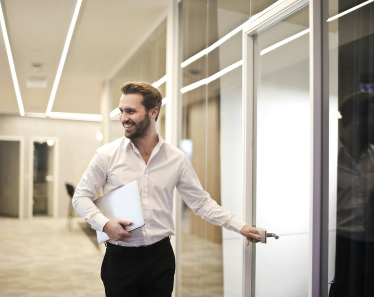 A man in a white shirt and black pants entering conference room in a business