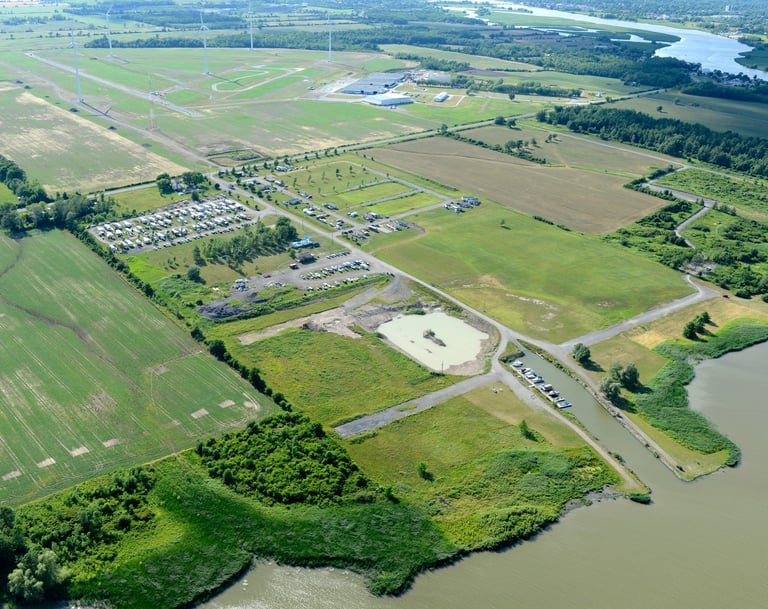 Aerial view of a rural campground and boat launch area near wind turbines and river wetlands.