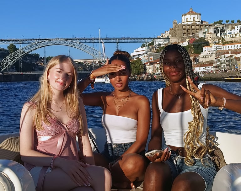 Three girls posing for a photo on the Endure speedboat with Dom Luís I Bridge in the background