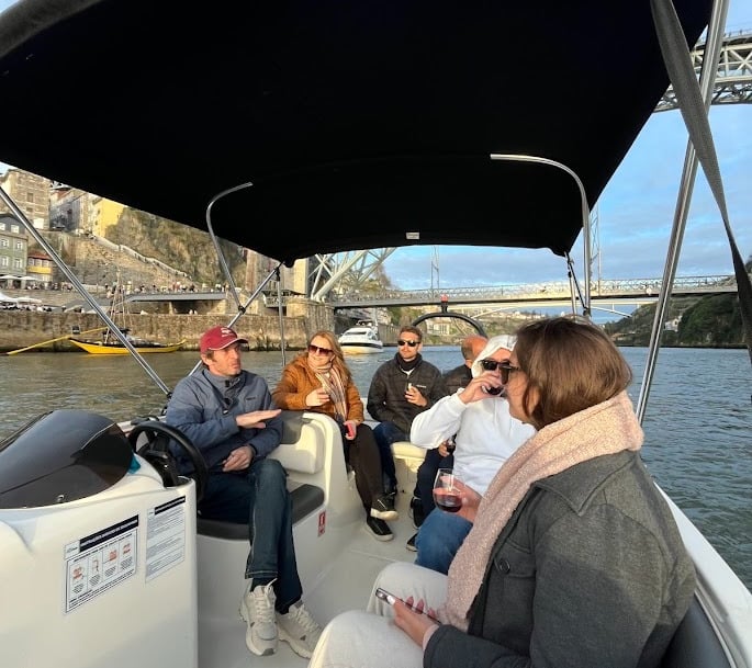 Guests chatting with Captain Francisco on Endure, with Porto’s Dom Luís I Bridge in the background