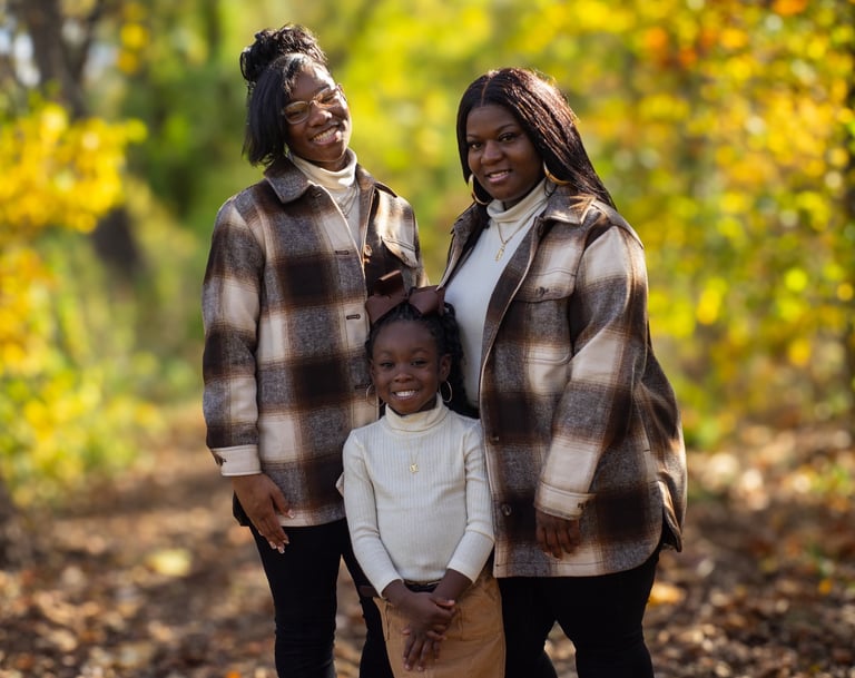 a family of three standing in a wooded area