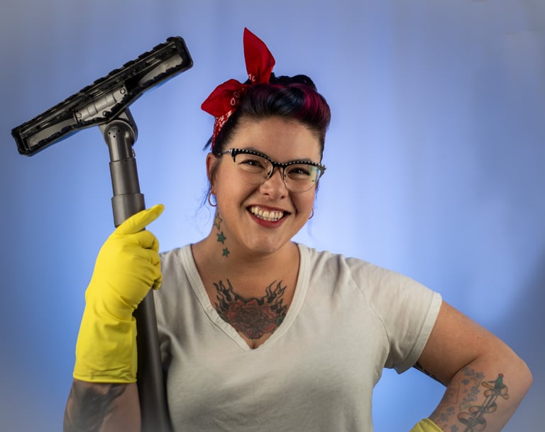 a woman with brown hair and a red bandana tied on her head holding a vacuum cleaner hose