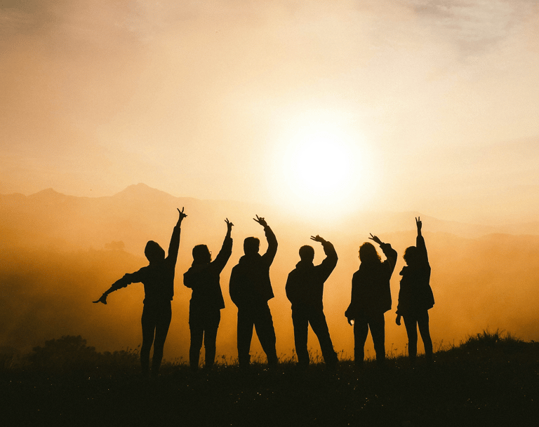 Silhouette of people on a mountain representing group lessons to improve proficiency and have fun