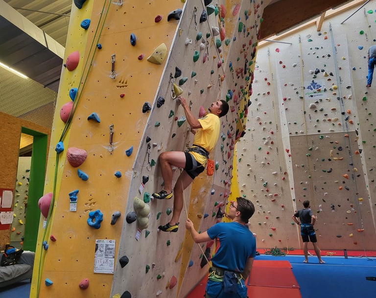 An indoor climbing course participant climbs on lead.