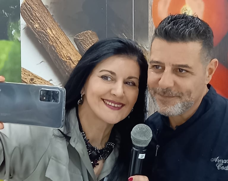 Clara Mennella intervista lo chef Armando Codispoti durante un evento gastronomico, riprendendo con smartphone e microfono.