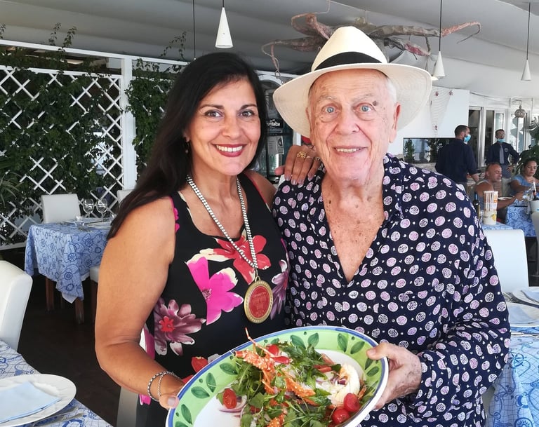Clara Mennella con il Professor Aldo Palmeri del Club Corone Oro Sicilia, mentre presentano un piatto gourmet in un ristorant