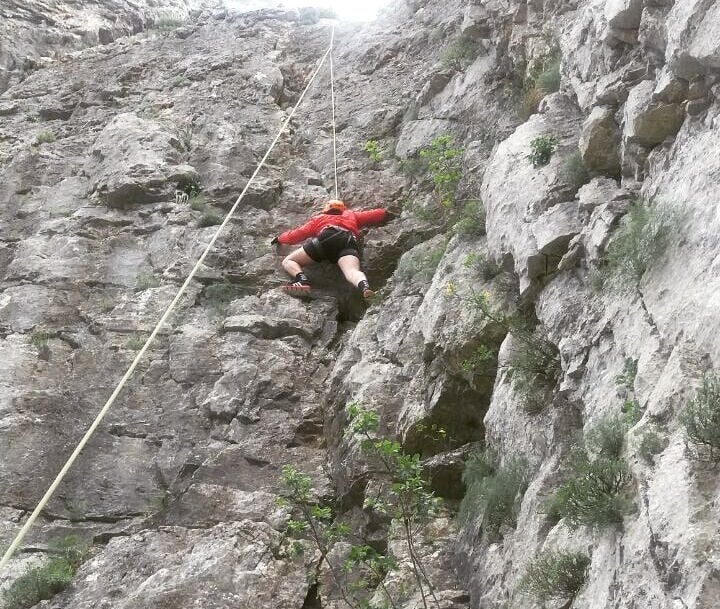a man in a red shirt is climbing a steeple
