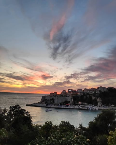 a sunset over a city with boats and a sunset