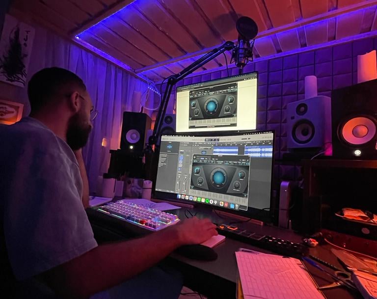 a man sitting at a desk with a laptop computer and a microphone in a studio making music in lebanon