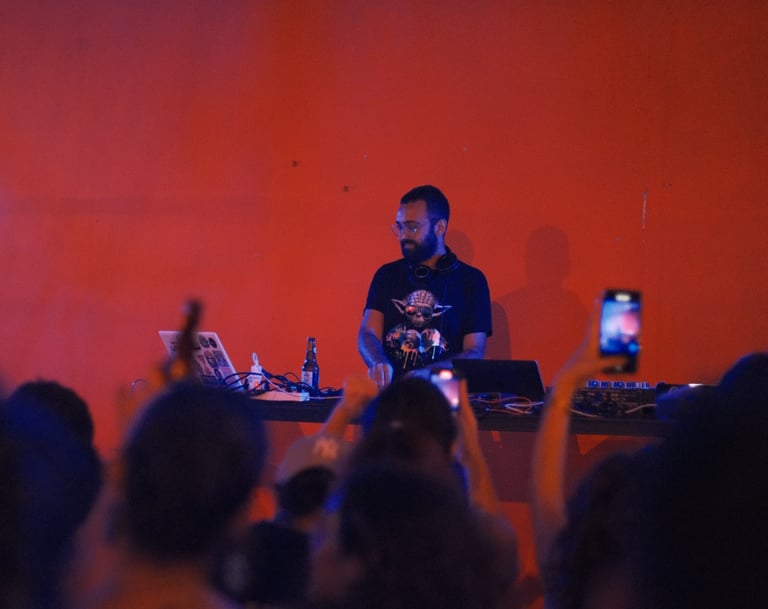 a man in a black shirt and a laptop on a stage djing with people taking pictures lebanon