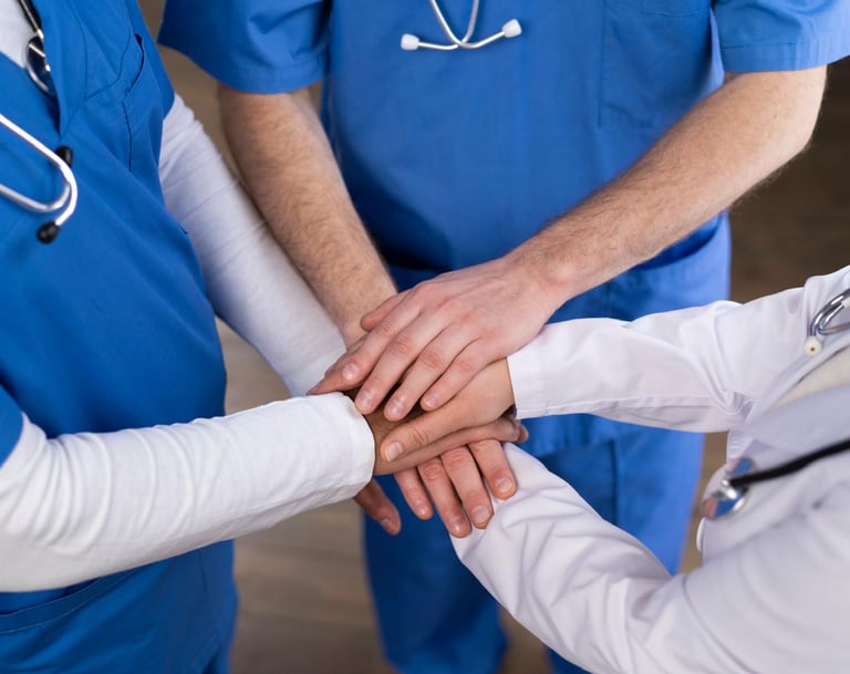 Profesionales médicos con las manos juntas, simbolizando el trabajo en equipo y la colaboración