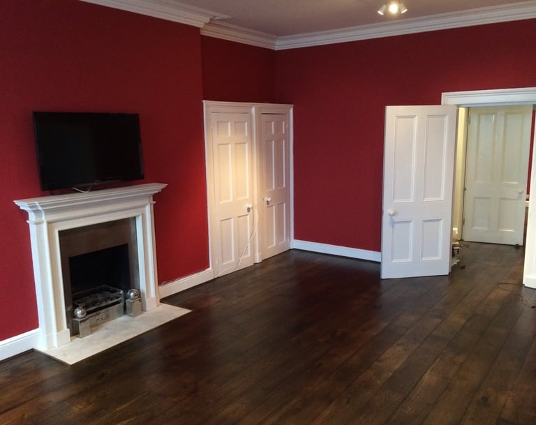 Brighton living room with bold red walls, white fireplace mantle, and matching white doors.