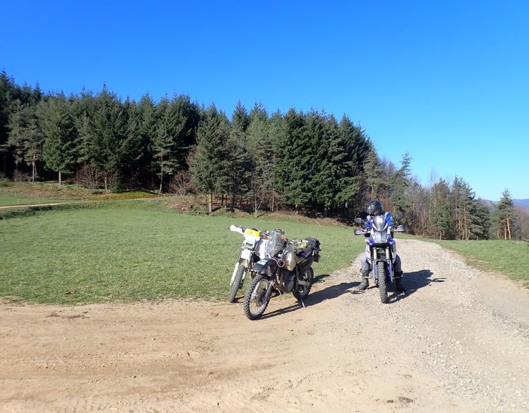 two motorcycles parked on a dirt road