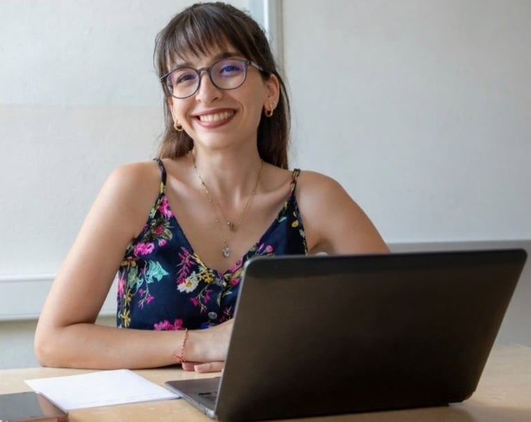Woman wearing glasses smiling at viewer with laptop