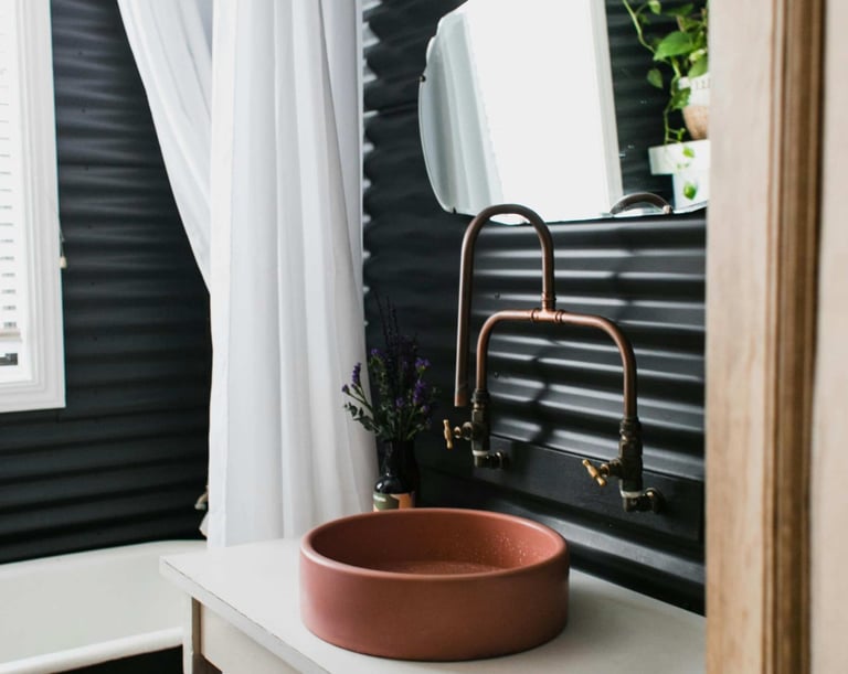 Modern bathroom with round basin and copper tap against dark panel wall