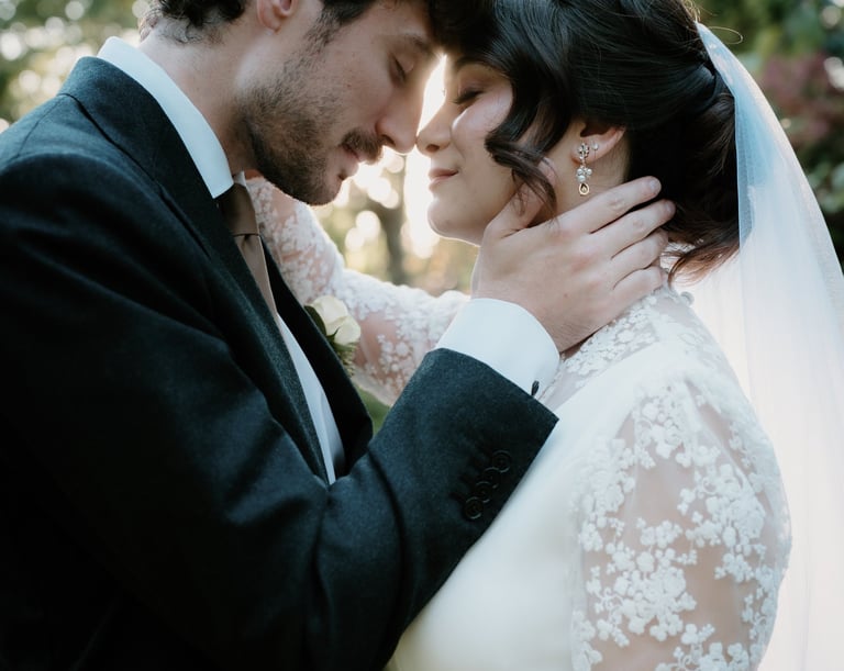Un marié en costume foncé enlaçant sa mariée dans une robe de mariée en dentelle lors d’une cérémoni
