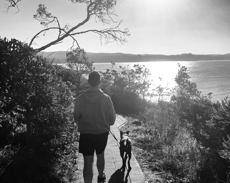 A headland path with a man walking a dog