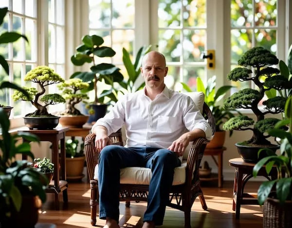 The Bonsai Boi in sunroom surrounded by his bonsai