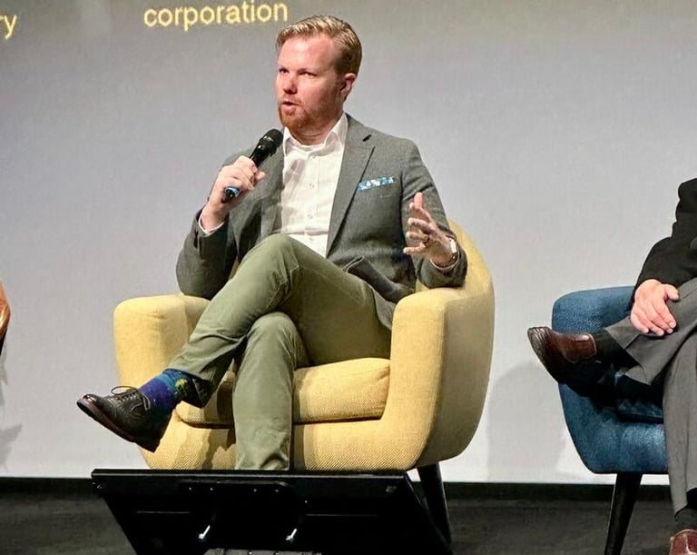 Nick Reese speaking on panel on emerging technology sitting in chair wearing green blazer