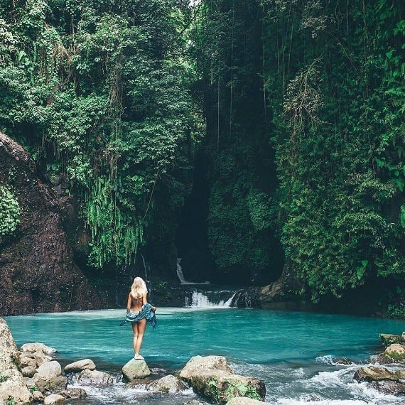 a woman standing on a rock in a river