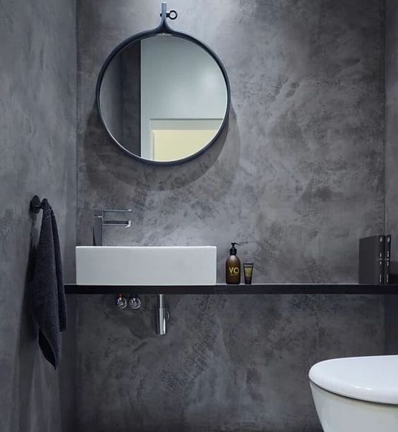Badkamer afgewerkt met Mortex pleister, met een ronde wastafel en spiegel.