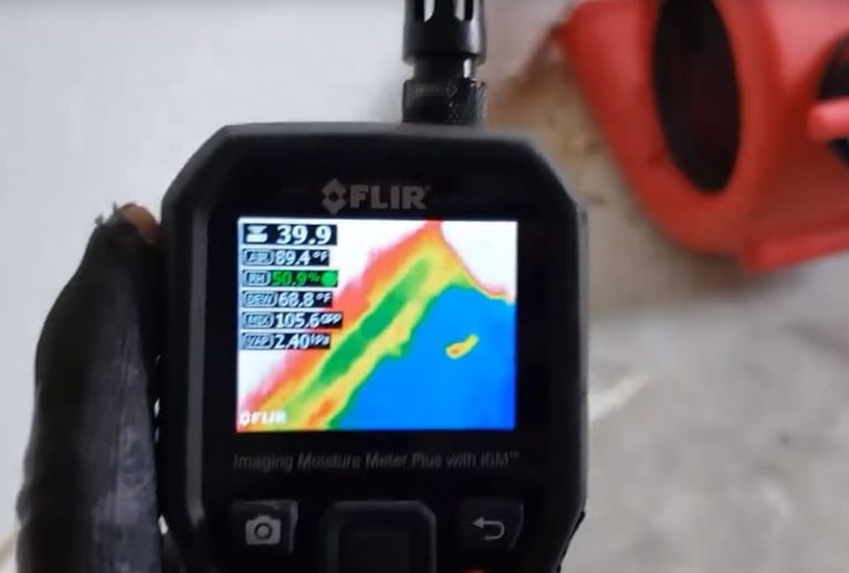 A FLIR moisture meter displays thermal imaging data for professional water damage restoration and leak detection.