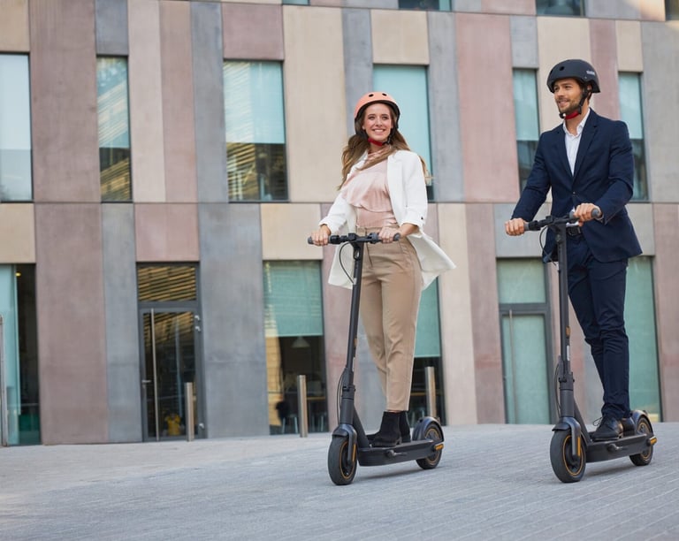 a man and woman riding scooters on a city street