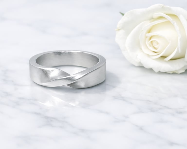 Handcrafted silver rings with smooth, minimalist finishes on a marble surface