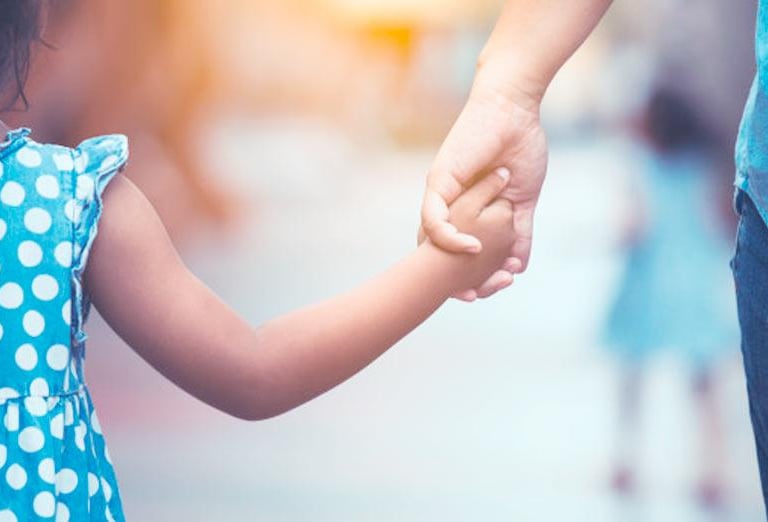 a young girl holding hands with her father