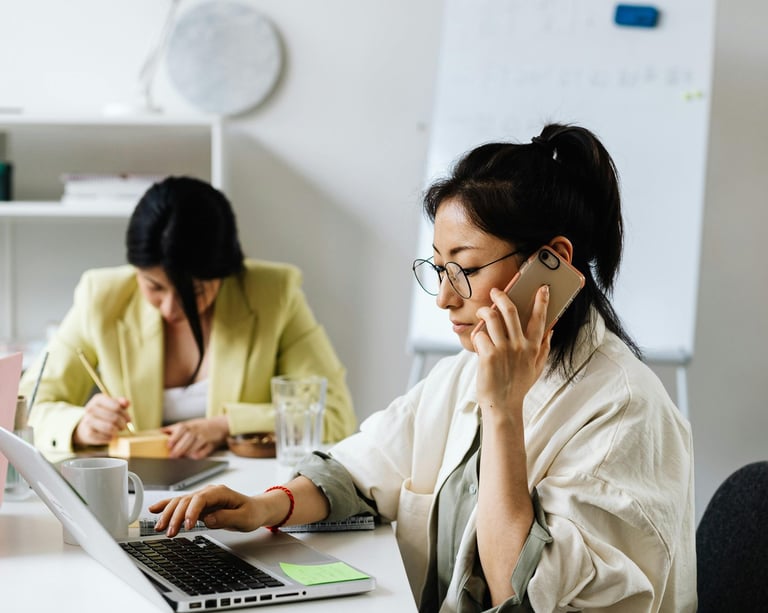 Support centre with two women answering phone call and replying to email.