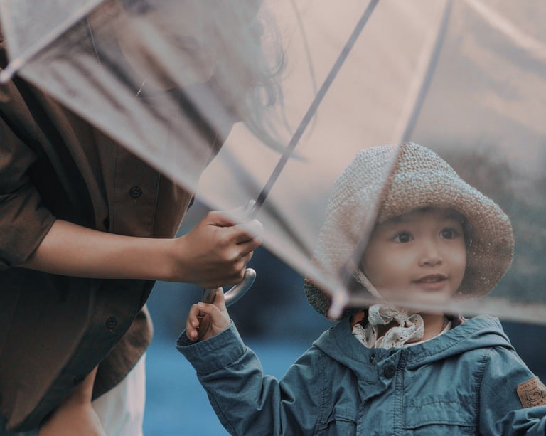 Uma mãe ajudando a filha a segurar um guarda-chuva para se proteger