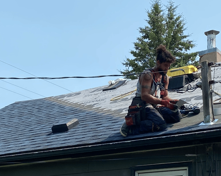 Professional roofing contractor installing new asphalt shingles on a residential house roof.