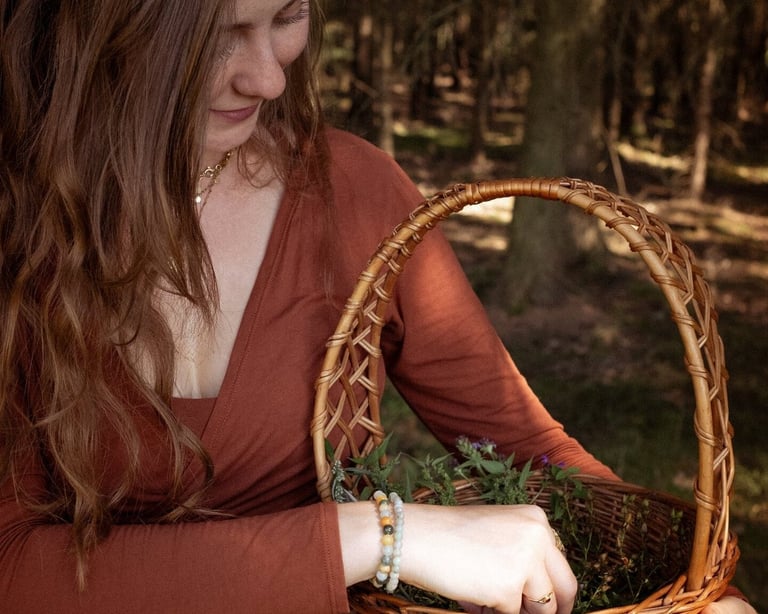 Eine Frau sammelt Kräuter in einem Korb, während sie in einem Wald steht.