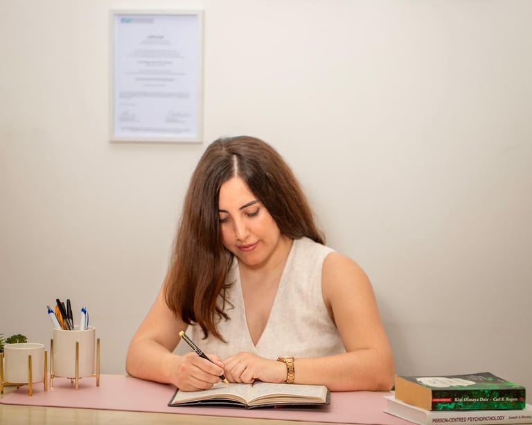 Psychotherapeutin Linda Acikalin sitzt am Schreibtisch und macht Notizen in ihrer Praxis.