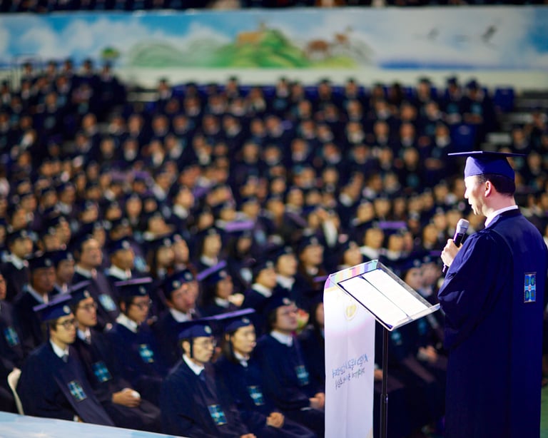 Um homem em uma beca de formatura falando em um microfone
