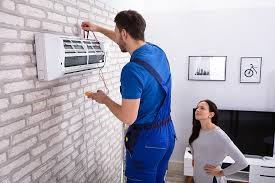 a man and woman standing in front of a wall mounted air conditioner